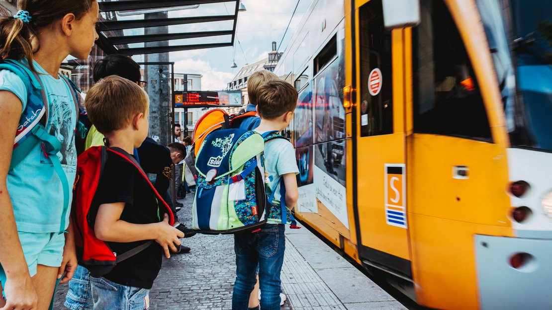 Kinder steigen an einer Halterstelle in eine Straßenbahn (Saarbahn) ein.